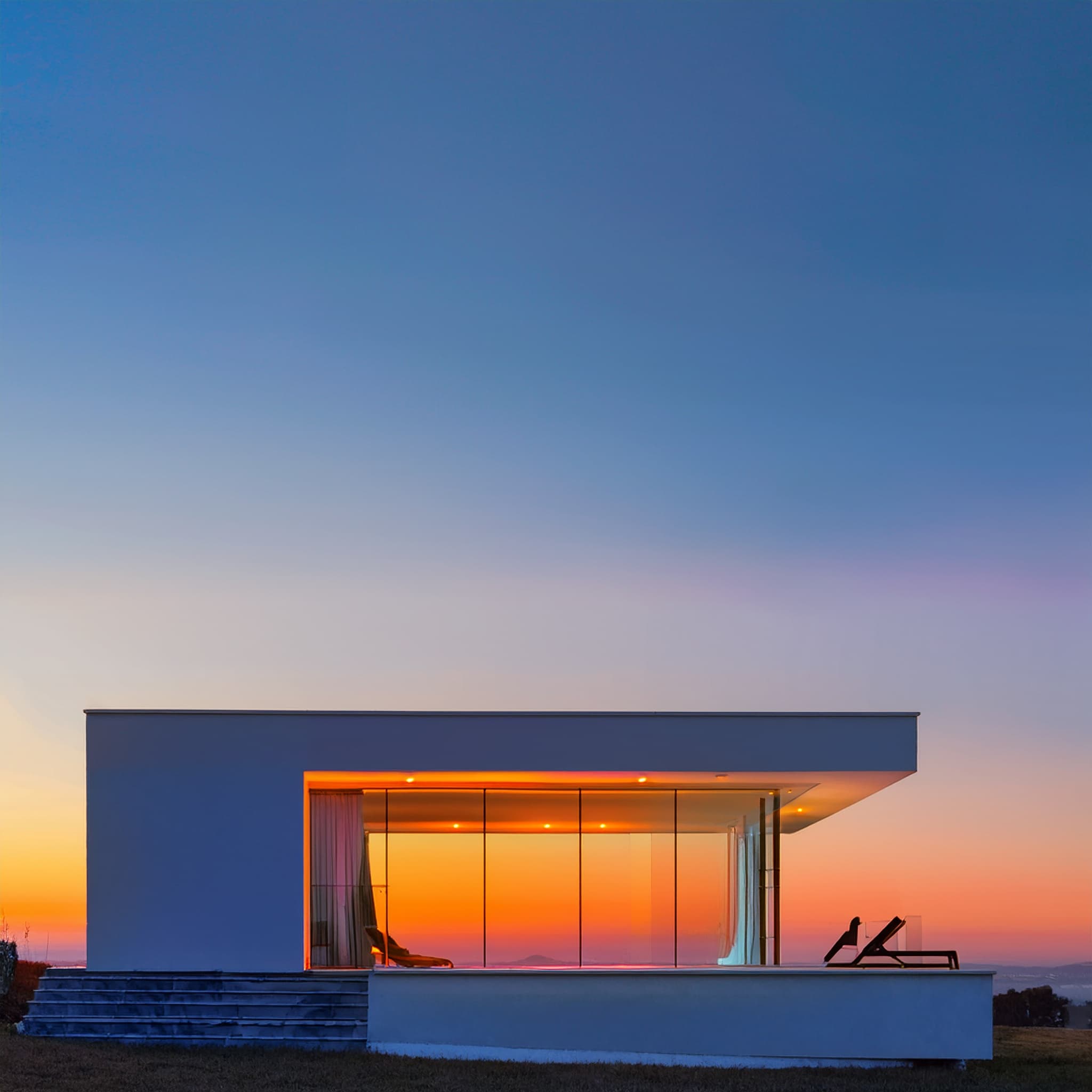 Casa minimalista frente al mar al atardecer.